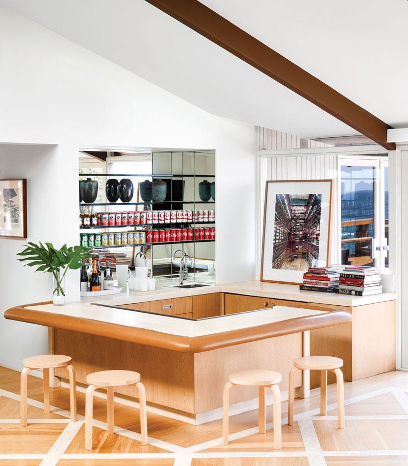 A Candida Höfer photograph is displayed in this Eddie Lee–designed residence’s sunken bar, which is topped with travertine and leather; the stools are by Alvar Aalto.