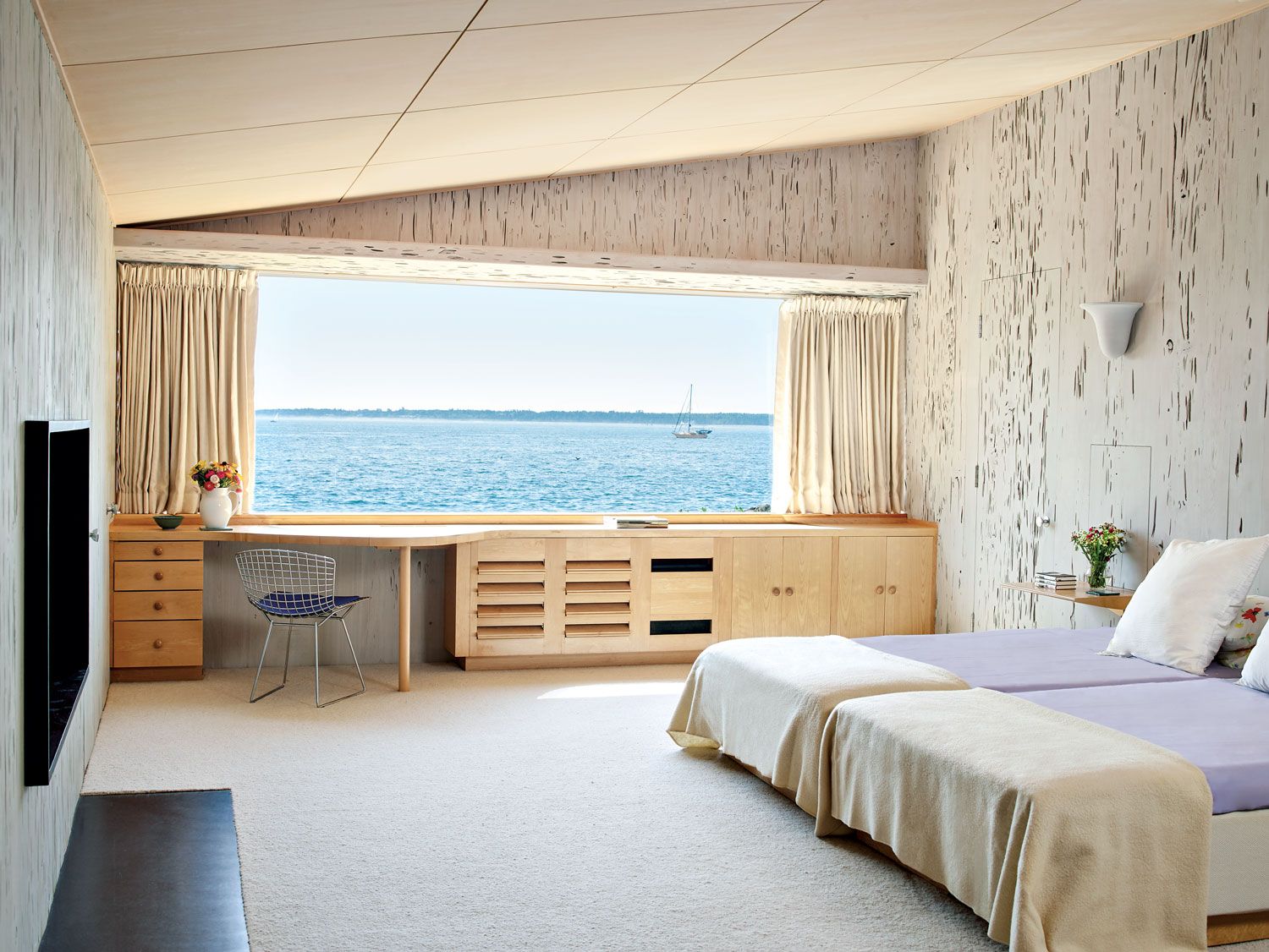 In the master bedroom, the walls are pecky cypress. The built-in cabinetry has the sleekly efficient look of an ocean liner, and the curved form of the desk reflects the shoreline beyond.