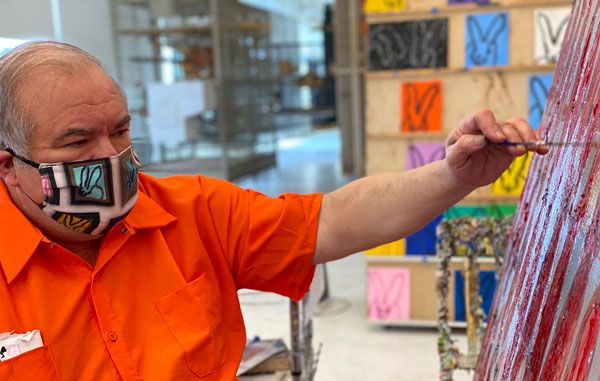 Hunt Slonem wears one of his face mask designs, available in his online Hop Up Shop, while painting in his Brooklyn studio.