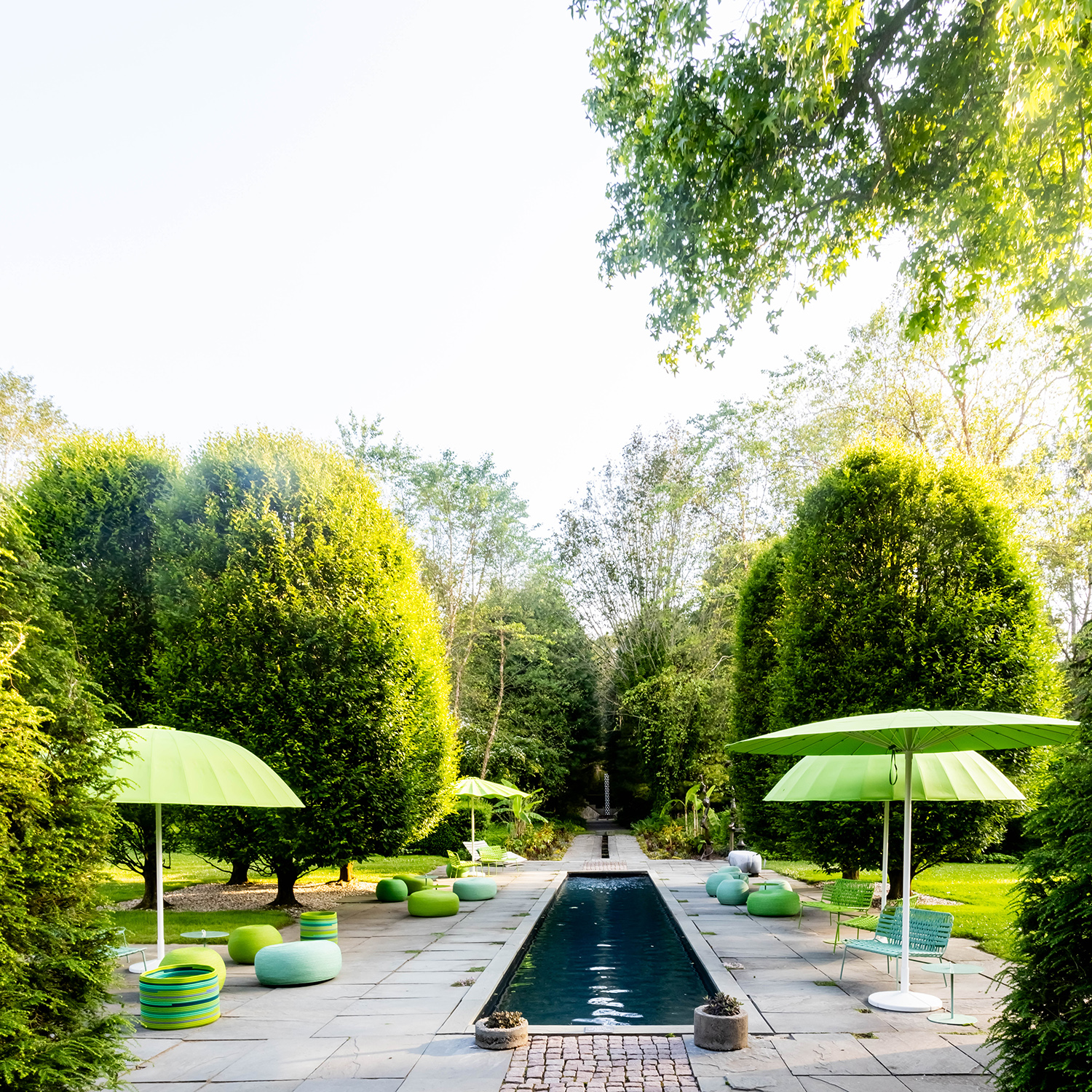 Paola Lenti Bistrò parasols, Otto poufs, and Telar armchairs installed around the pool at the LongHouse Reserve in East Hampton.