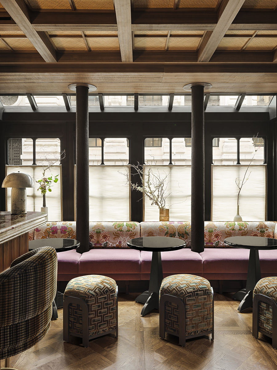 Designer Laura Gonzalez chose floral Jacquard silks and pink velvet for the banquettes in the bar to the right of the black lava counter that serves as the reception desk at Hotel Hana in Paris.