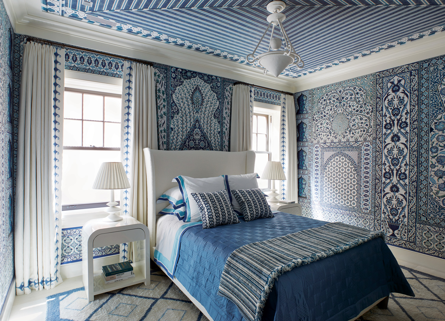 For a downstairs guest room in the Hamptons, Stewart Manger enveloped the space in an exuberant Iksel wall covering customized in shades of blue, with a rug by Beauvais Carpets commissioned in a matching palette.