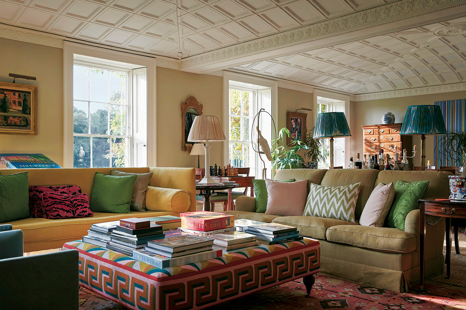 Beneath the drawing room’s restored plaster ceiling, a yellow Max Rollit sofa and a vintage Howard & Sons sofa clad in a Claremont linen face an ottoman table upholstered in a fabric Ben Pentreath commissioned from Fine Cell Work; a Pentreath & Hall lamp stands on one of the antique side tables, the matching pair of lamps are by Robert Kime, and the rug is antique.