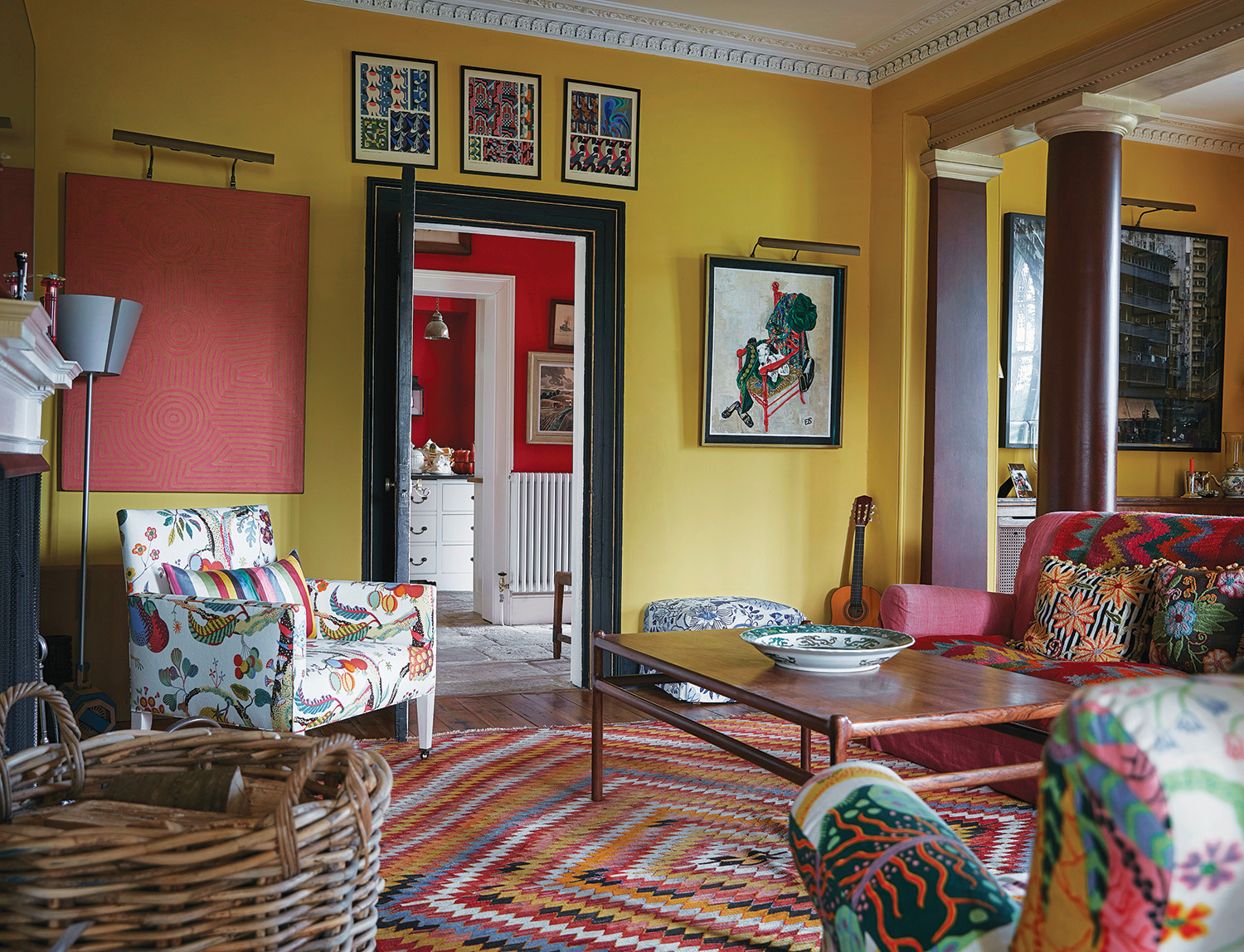 In the family room reimaged by Ben Pentreath, walls painted in Imperial Chinese Yellow by Papers and Paints provide a lively backdrop for pieces such as the Aboriginal painting mounted to the left of the doorway.