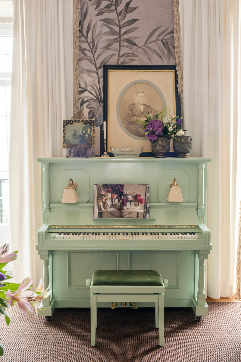 A painted antique piano fronts an expressive wallpaper by Ananbô in the bar area of Solar de Vila Meā in Barcelos, Portugal.