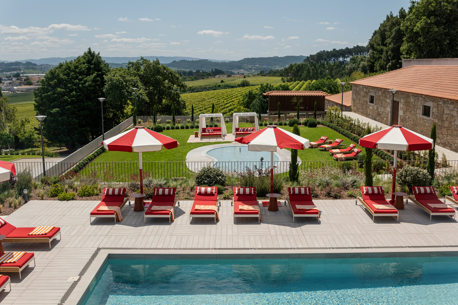 Point loungers and Kettal side tables are topped with cheery parasols customized by Joana Aranha Studio at Solar de Vila Meā in Barcelos, Portugal.