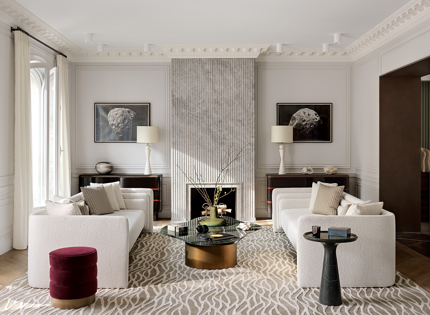 In the living room, an elegantly fluted marble fireplace surround is flanked by Nicolas Moulin graphite drawings, which surmount cabinets by Damien Langlois-Meurinne, who also designed the red velvet stool and rug.