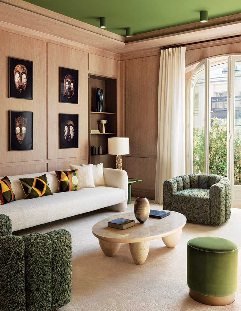 In the family room of a Paris residence renovated by designer Damien Langlois- Meurinne, photographs of African masks by Thierry Fontaine are mounted on cerused-oak paneling above a Collector sofa grouped with custom lounge chairs.