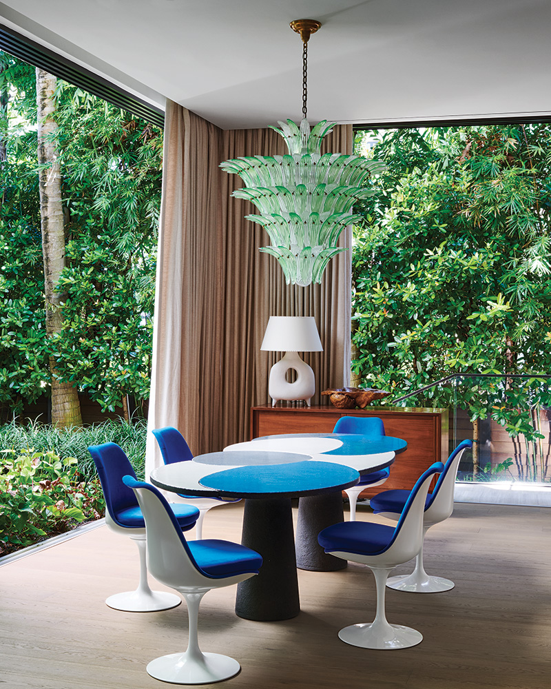 A Barovier & Toso chandelier shimmers above an Emmanuel Babled table paired with Eero Saarinen Tulip chairs in a Miami home designed by Georgis & Mirgorodsky.