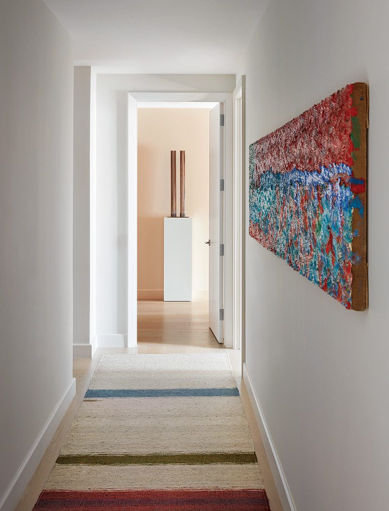 A Dashiell Manley wall work and an ALT for Living rug adorn the hallway, which leads to a sculpture by Harry Bertoia in the penthouse by Shawn Henderson.