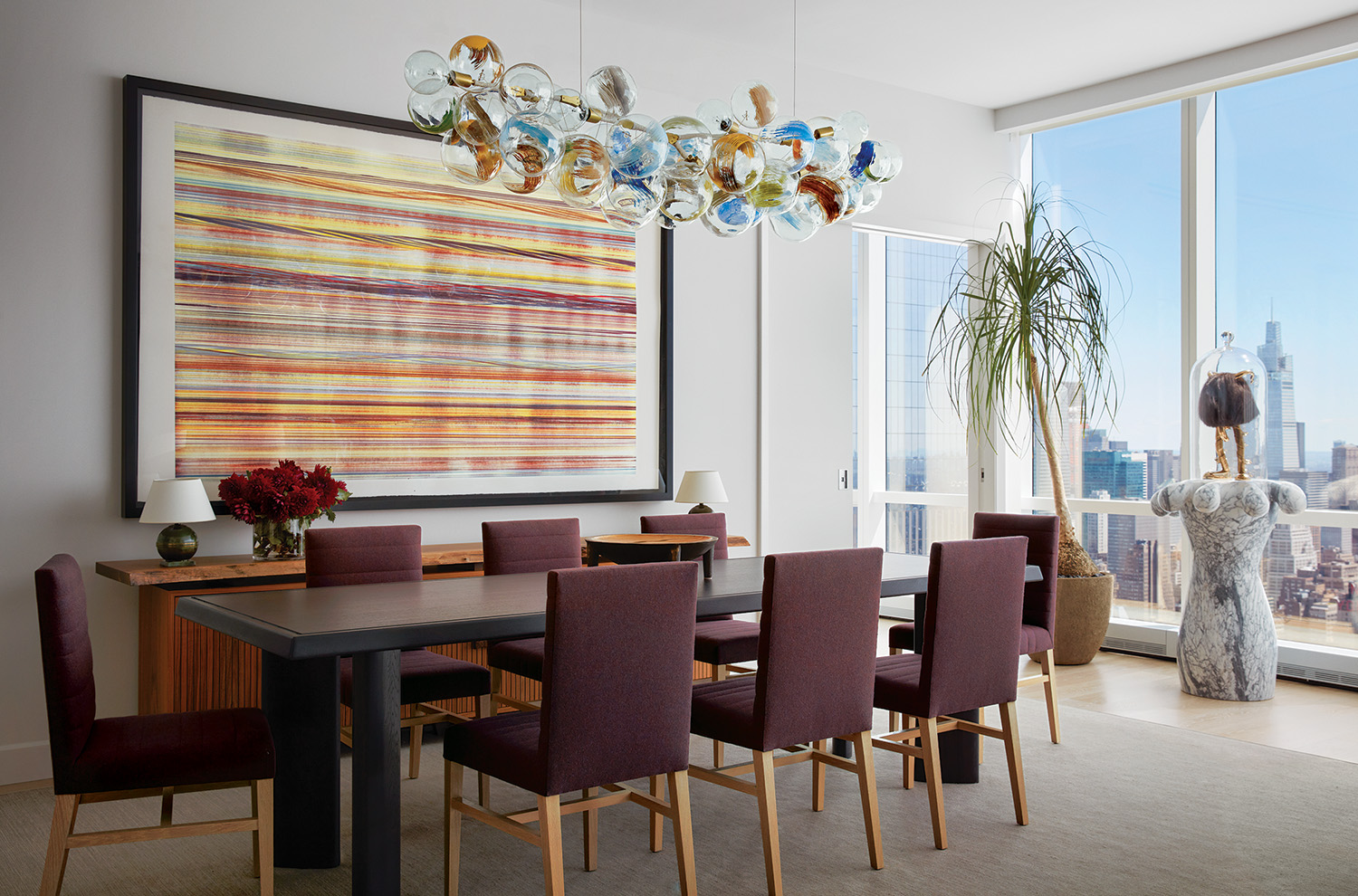 In the dining room by Shawn Henderson, a brightly hued Pelle light fixture and a Jamie Nares artwork contrast the more subdued tones of the Haas Brothers sculpture and custom table and chairs.