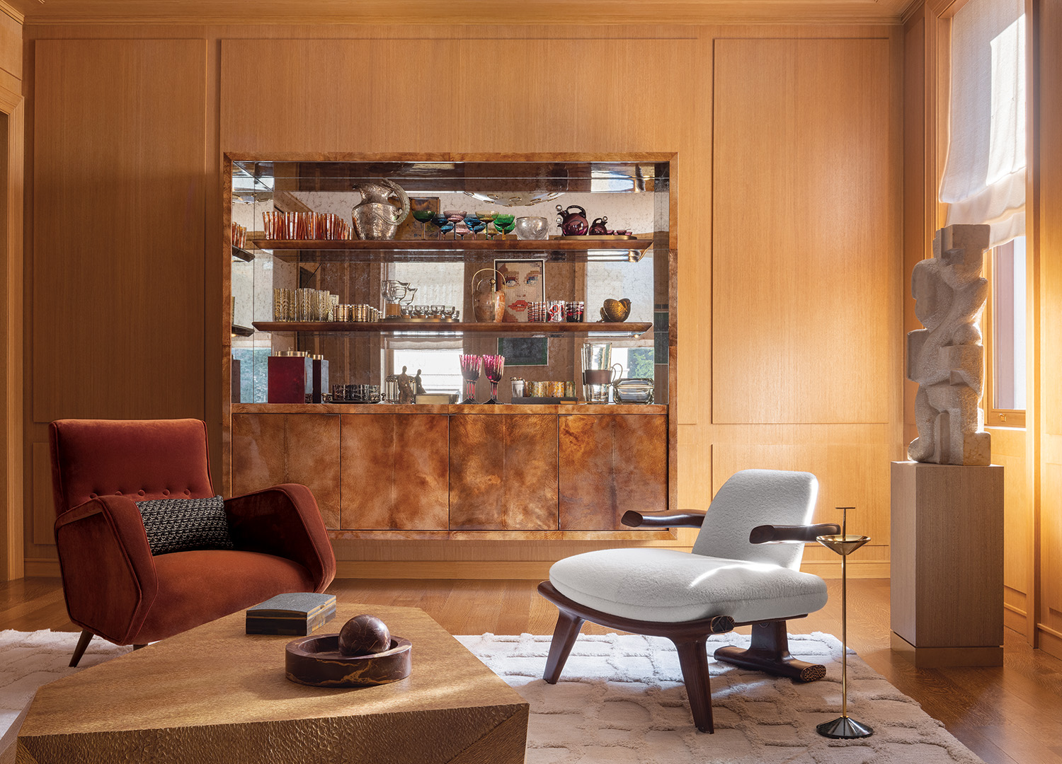 A Naomi Feinberg sculpture rests on a pedestal near the living room’s bespoke bar, finished in stained and lacquered vellum and antiqued mirror.