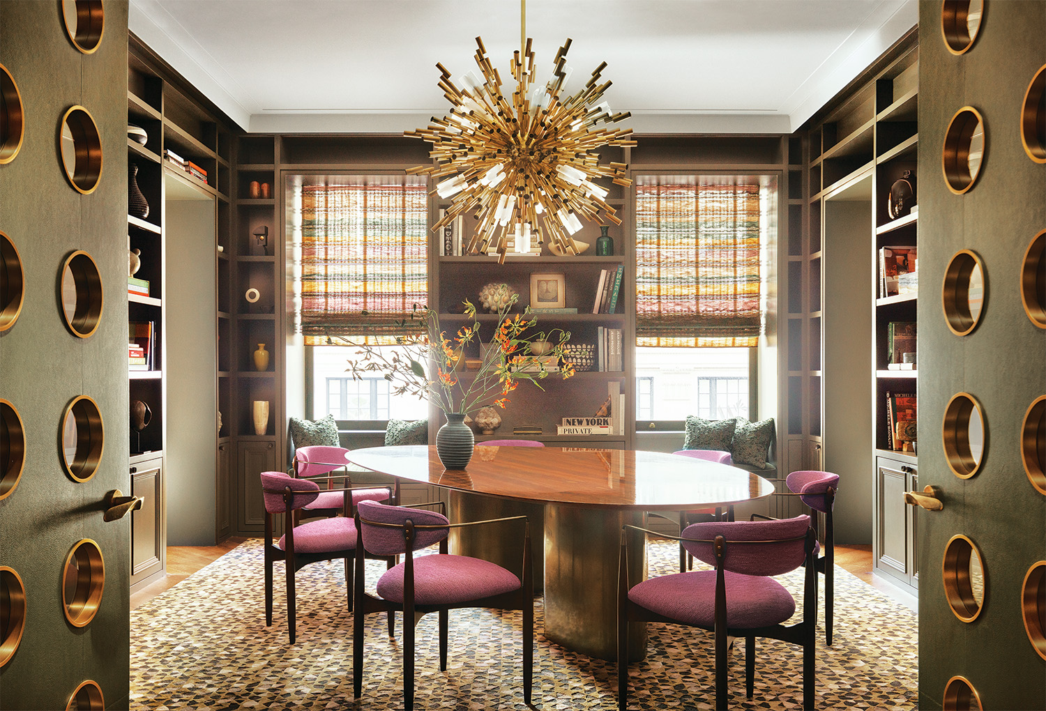 Jean Prouvé–inspired doors, wrapped in a Holly Hunt leather, open to the dining room, where a vintage chandelier radiates above a custom-made table with a rosewood-veneer top and vintage Dan Johnson chairs; the rug is by Holland & Sherry.