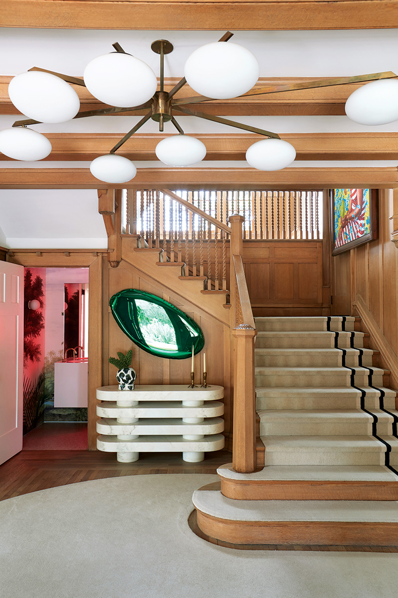 The traditional wood stairway in the Los Angeles home of architect Chet Callahan, designed by Ghislaine Viñas, boasts a Joris Poggioli console, a Zieta mirror, and a custom runner by The Rug Company.