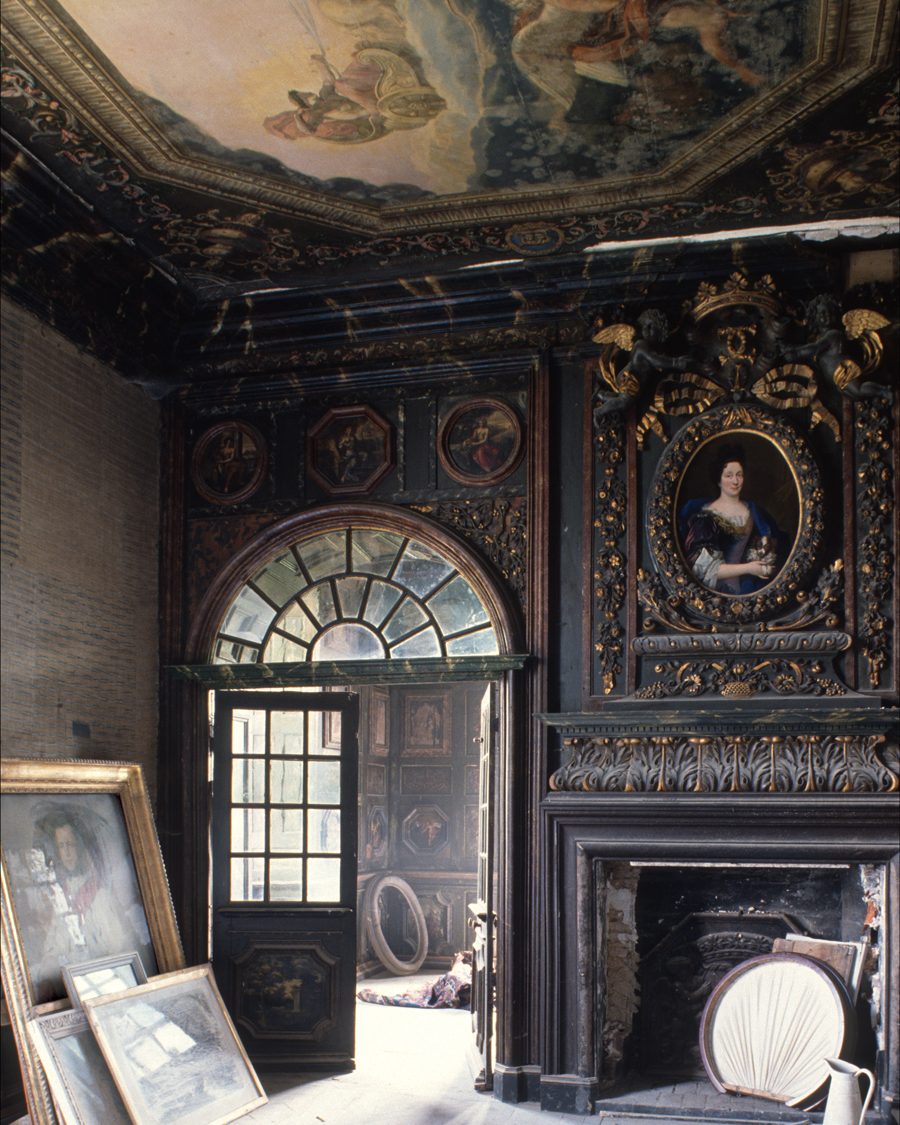 A grand reception room with ornate carved and gilt paneling and painted ceiling is an ideal storage room for unwanted art.