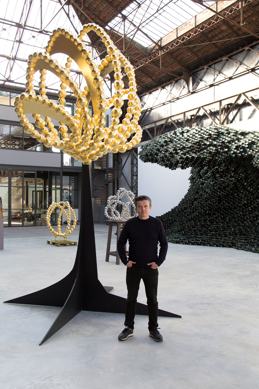 Jean-Michel Othoniel and his work in stainless steel and gold leaf Gold Lotus of 2022. The glass Big Wave of 2017 is behind.