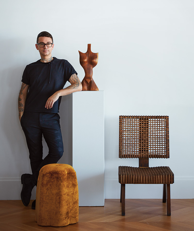 Designer Christian Siriano with a treasured Pierre Jeanneret chair, plus a sculpture by an unknown artist and a Lily stool from his namesake home collection.