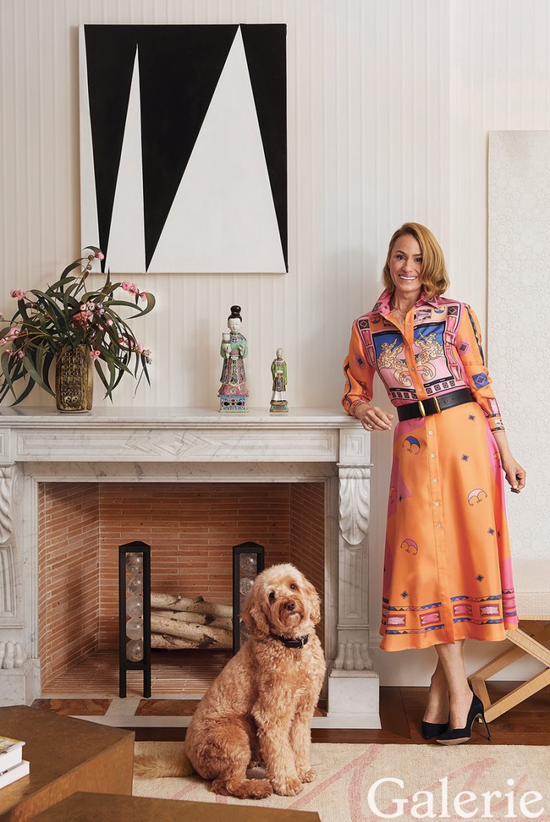 Astrid Hill stands with her dog, Modi, by the living room’s Charles X–style marble fireplace, styled by Frank de Biasi.