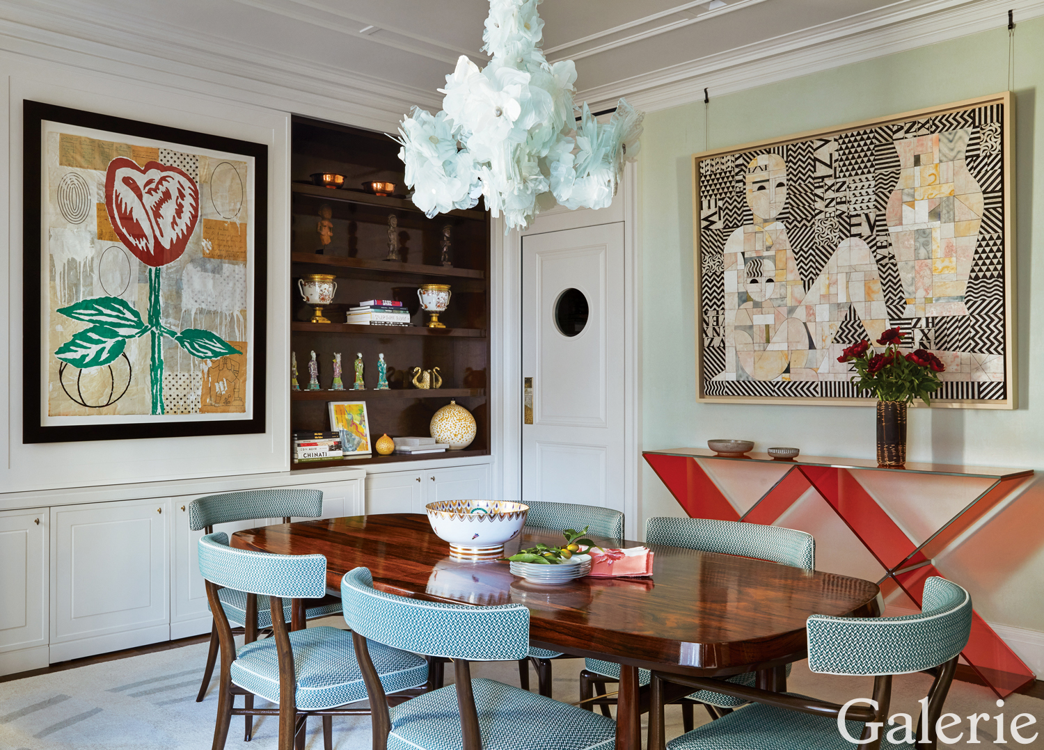 In this space designed by Frank de Biasi, a Nathalie Ziegler chandelier is mounted above the dining room’s midcentury Scandinavian table and chairs, a Donald Baechler work hangs next to the shelves, and a painting by Ruby Sky Stiler is displayed above a Johanna Grawunder console for Glas Italia.