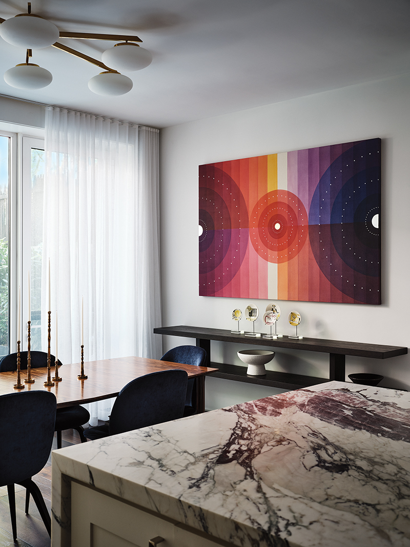 A Field Kallop canvas surmounts a custom console in the kitchen, where a bespoke rosewood table is set with Gubi chairs.