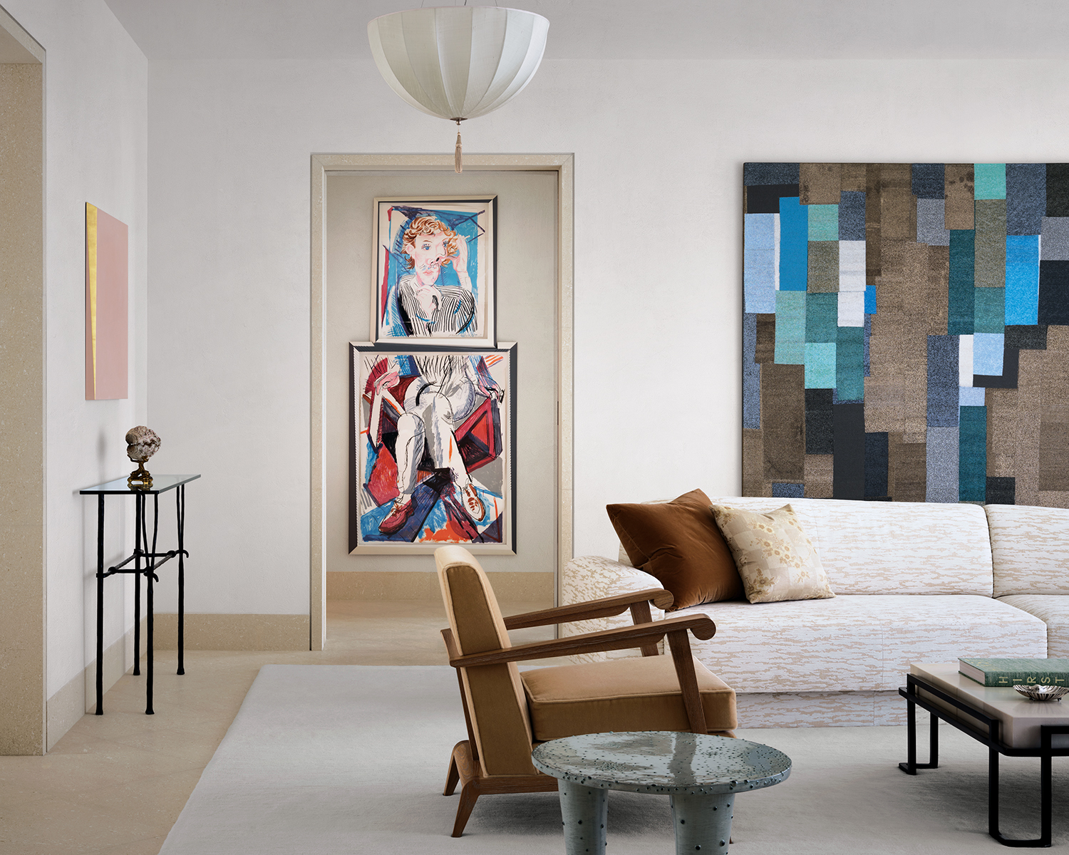 In the living room, an Ettore Spalletti painting surmounts a Garouste & Bonetti console, a David Hockney print is visible through the doorway, and a geometric beaded work by Liza Lou hangs behind a custom sofa upholstered in a Toyine Sellers fabric. The parchment-top cocktail table is by Alexander Lamont, and the pendant is a Josef Hoffmann design from Woka Lamps Vienna.