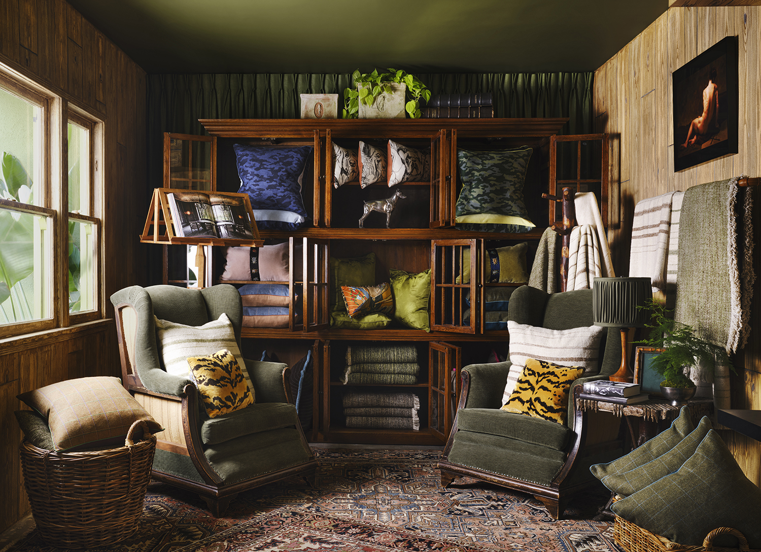 Vintage green corduroy wingback chairs are paired with a variety of pillows in the faux bois-paneled library at Ken Fulk’s new store in Los Angeles.