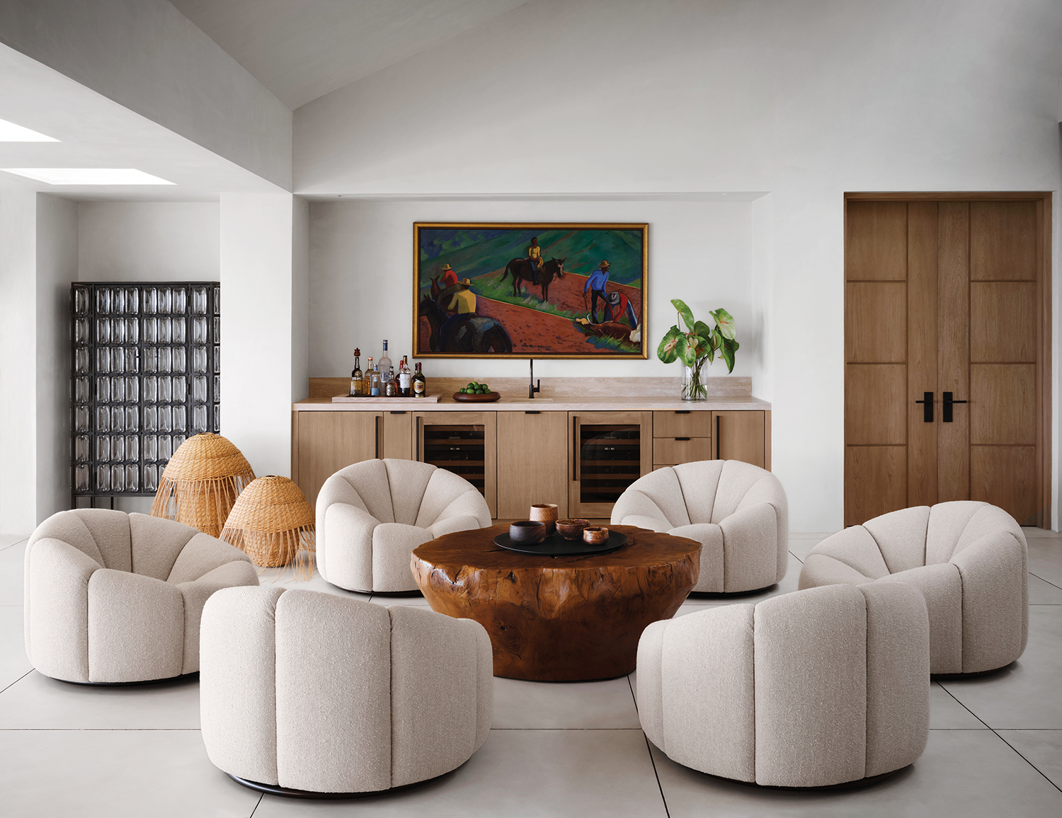 Pierre Paulin swivel chairs from Ralph Pucci surround a teak-root cocktail table in the lounge, where a Robert Lee Eskridge painting hangs above the custom travertine-top teak bar and Cristián Mohaded woven-fiber sculptures perch next to a cast-glass cabinet by Christophe Côme.