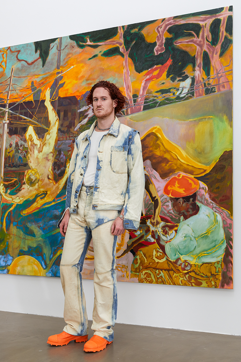 Portrait of the artist Blake Daniels in front of a painting.