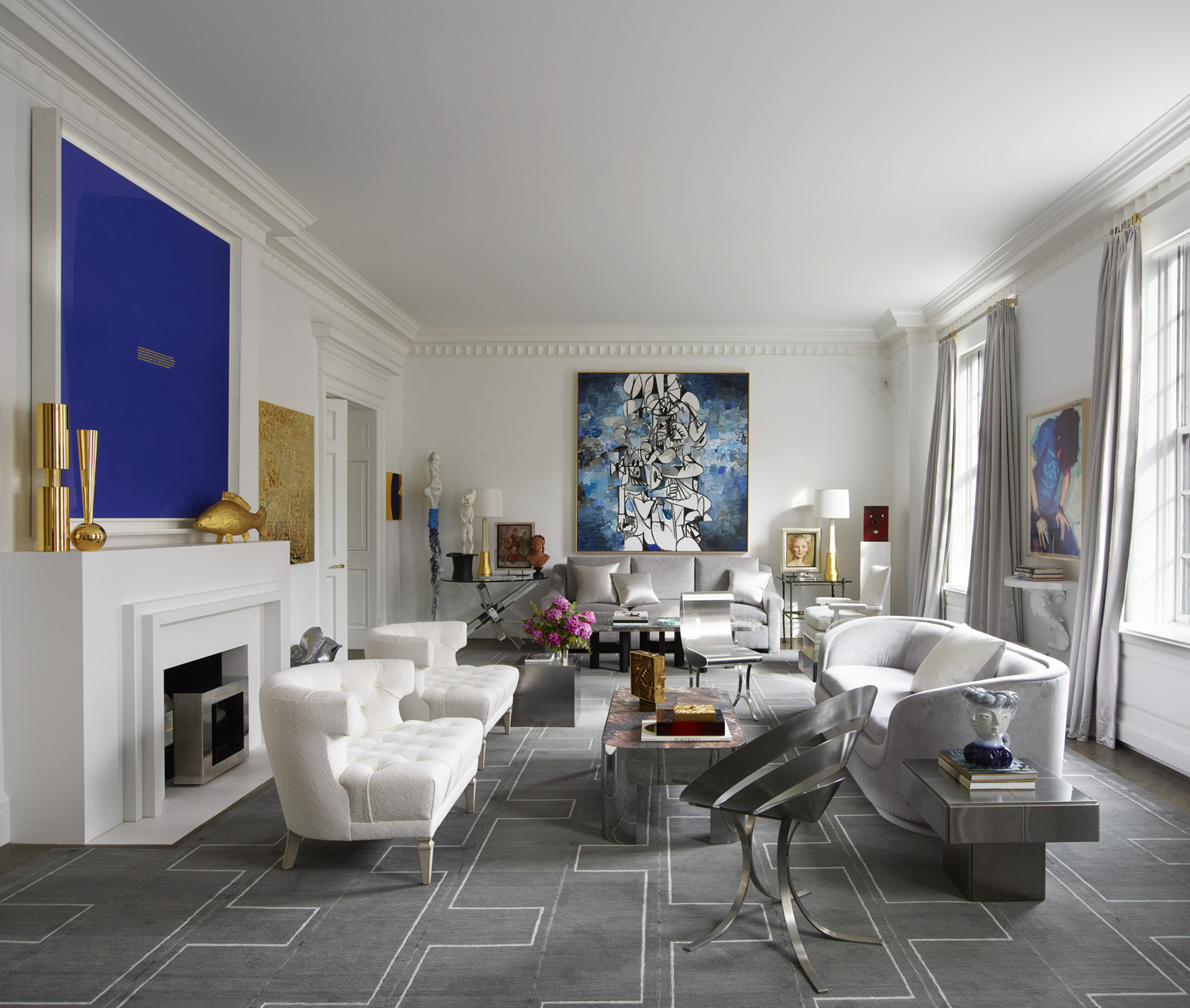 Works by Richard Prince (above the mantel) and Rudolf Stingel (to the right of the mantel) and George Condo (above the sofa) are displayed in the living room. The mantel hosts a François-Xavier Lalanne fish. The metal chairs are by Maria Pergay, and the carpet was custom-made by Holland & Sherry.