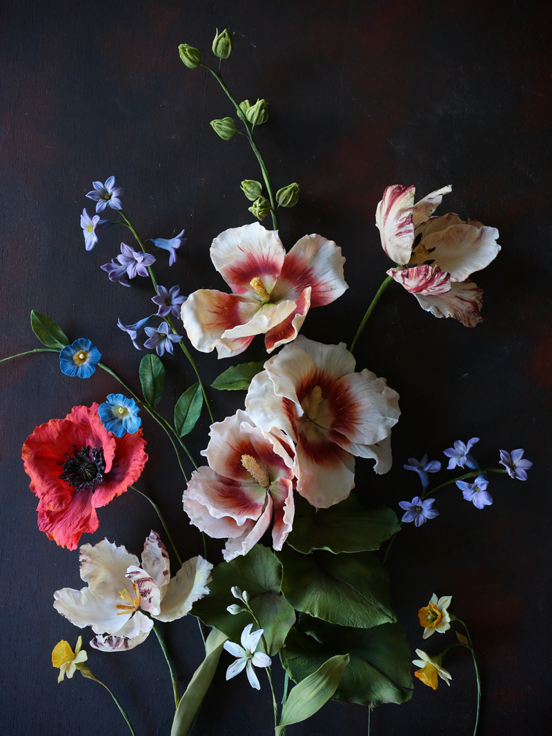 A collection of sugar flowers, sugar hollyhock, tulips, wild hyacinth, morning glory and daffodils.