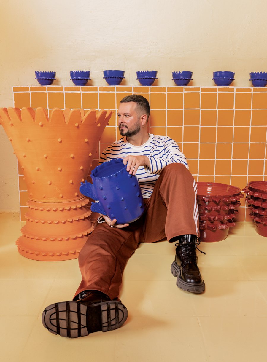 Daniel Valero holding the Copli vase and seated among planters from the Los Tabanchines collection by Mestiz.