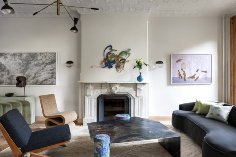 Contemporary living room with abstract art, diverse seating, and a decorative fireplace mantel.