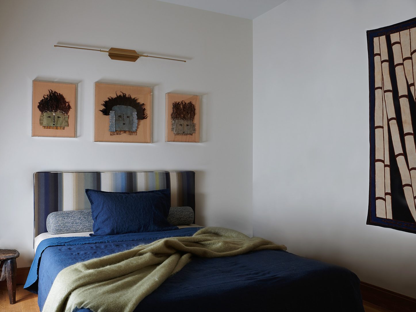 In the primary bedroom, a trio of rare early-19th-century Navajo Yei masks hangs above a custom maple platform bed.