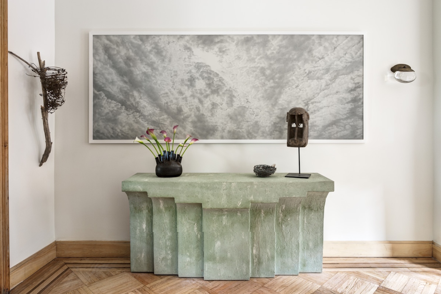 A graphite drawing of clouds by Sajjad Nawaz sits above a mint green plaster console in the living room.